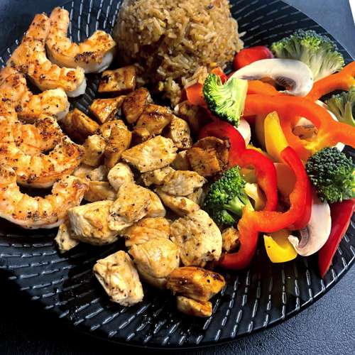 Plate of hibachi chicken and shrimp with fried rice and vegetables