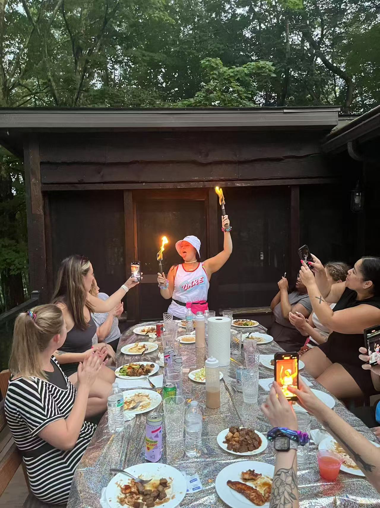 Hibachi chef breathing a tall column of fire over the grill at a backyard night party